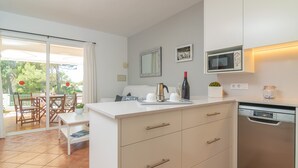 A modern kitchen with white cabinets, a built-in microwave, and a dishwasher. - SES FONTS C25 - Charming flat with shared pool and close to the beach. Free WiFi. (Es Mercadal)