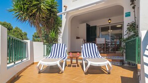 A terrace with two striped lounge chairs, a small table, and a potted plant. - SES FONTS C25 - Charming flat with shared pool and close to the beach. Free WiFi. (Es Mercadal)