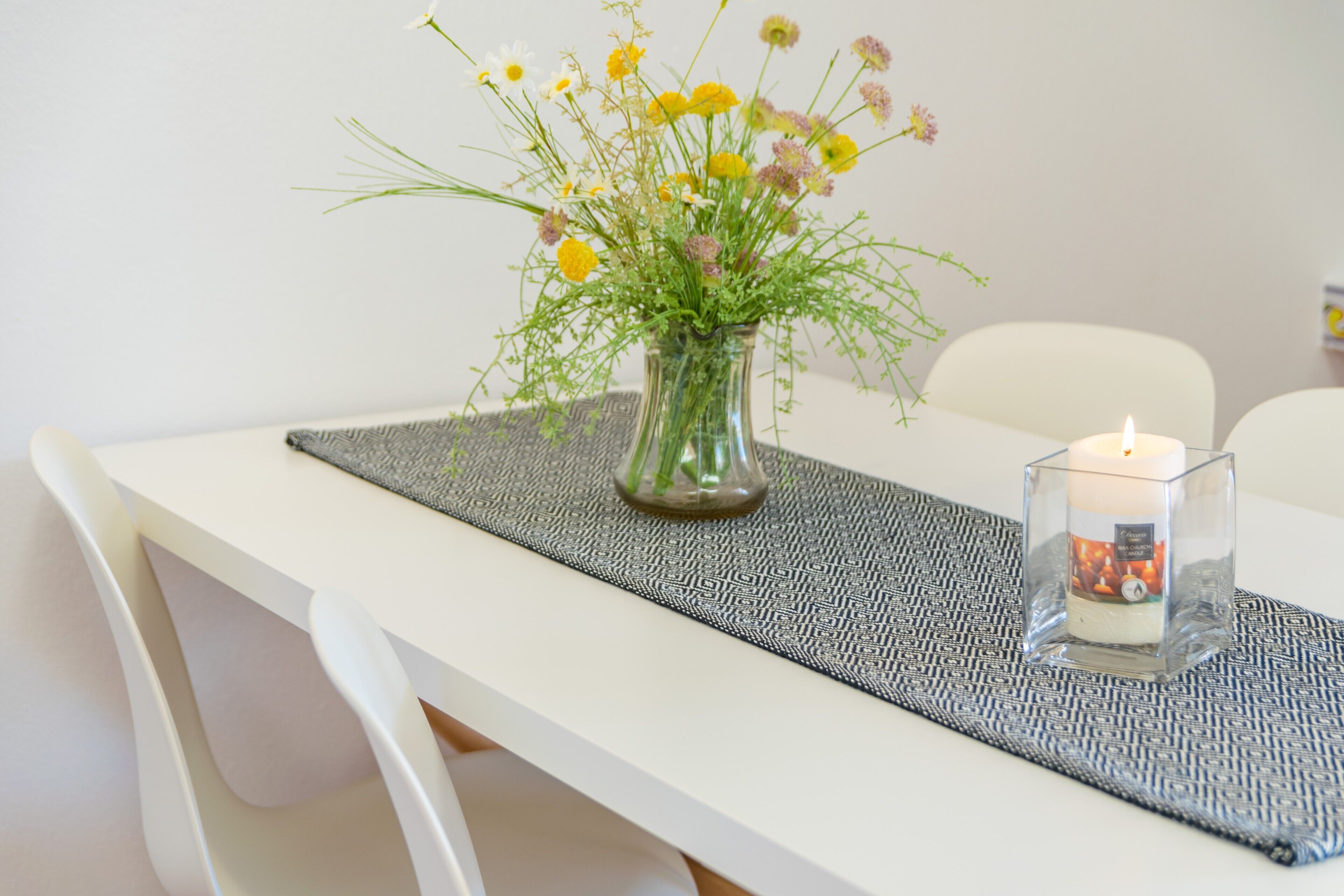 Een eettafel met een bloevas en een kaars.