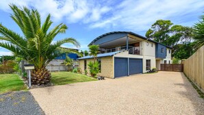 Une maison à deux étages avec un porche couvert, un garage et une allée gravillonnée.