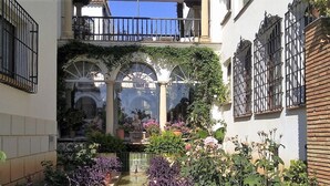 Ein Innenhof mit Kübelpflanzen, einer Fontäne und einer Statue.