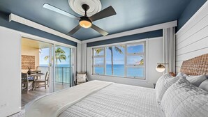 Ein Schlafzimmer mit einem großen Bett, einem Deckenventilator und Meerblick durch die Fenster.