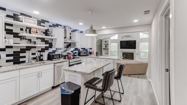 A modern kitchen with white cabinets, a granite countertop, a built-in oven, and a large island with bar stools. - Amazing! ATnT Stadium Rangers New Ball Park, Six Flags, Hurricane Harb Tex Live! (Arlington)