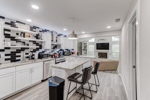 A modern kitchen with white cabinets, a granite countertop, a built-in oven, and a large island with bar stools.