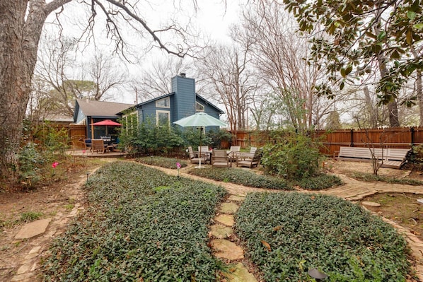 A backyard with a patio, a wooden deck, and a garden path.