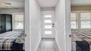 A narrow hallway with a door at the end, flanked by two bedrooms with beds and window blinds. - Amazing! ATnT Stadium Rangers New Ball Park, Six Flags, Hurricane Harb Tex Live! (Arlington)