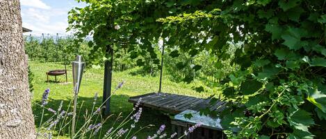 A rustic outdoor area with a wooden structure, a metal stand, and a tree.