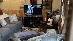 A living room with a sofa, a television, and a decorative wall with a bear picture.