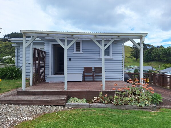 A house with a covered porch, a wooden deck, and a garden with various plants.