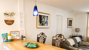 Cocina con encimera de madera, armarios blancos y una lámpara colgante azul.