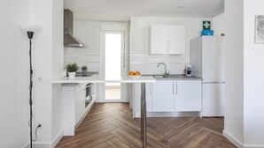 A modern kitchen with white cabinets, a stainless steel refrigerator, and a herringbone wood floor. - B-High quality apartment 3 bedrooms, 2 bathrooms pool Alcalá - Aral (Algaba)