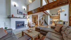 A spacious living room with a fireplace, leather sofas, and a wooden coffee table. - Northern Lights 21 – Ski in Walk out, Private Hot Tub, Fireplace (Whistler)