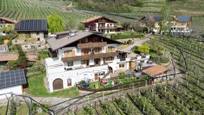 A multi-story building with a balcony, surrounded by vineyards and solar panels. - Holiday Apartment 'Rasnerhof Ferienwohnung Meran' with Mountain View, Balcony & Wi-Fi (Algund)