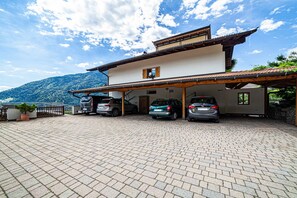 A two-story building with a covered parking area, a mountain view, and a paved driveway.