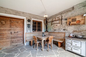 A rustic kitchen with a stone floor, wooden furniture, and a vintage stove.