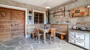 A rustic kitchen with a stone floor, wooden furniture, and a vintage stove. - Holiday Apartment Rasnerhof - Tschigat with Mountain View, Balcony & Wi-Fi (Algund)