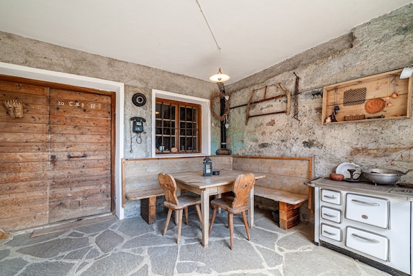 A rustic kitchen with a stone floor, wooden furniture, and a vintage stove. - Holiday Apartment Rasnerhof - Tschigat with Mountain View, Balcony & Wi-Fi (Algund)