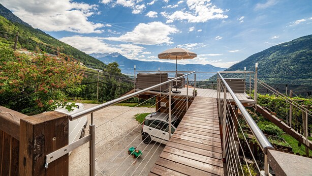 A wooden deck with a car and a toy car, overlooking a mountainous landscape.