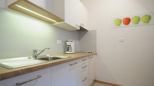 A kitchen with a sink, a coffee maker, and cabinets. - Holiday Apartment Rasnerhof - Tschigat with Mountain View, Balcony & Wi-Fi (Algund)