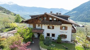 Un chalet traditionnel dotĂ© dâun balcon, avec un vignoble en arriĂšre-plan et un paysage montagneux.