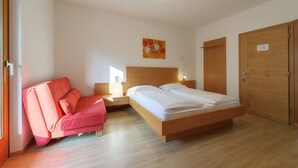 A bedroom with a bed, a nightstand, a chair, and a wooden wardrobe. - Holiday Apartment Rasnerhof - Tschigat with Mountain View, Balcony & Wi-Fi (Algund)