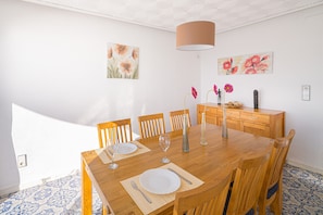 Zona pranzo con tavolo in legno, sedie e un lampadario.