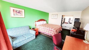 A hotel room with a bed, a sofa, a desk, and a chair. - Roadside Inn (Osceola)
