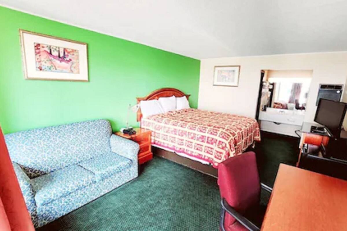 Ein Hotelzimmer mit Bett, einer Couch, einem Schreibtisch und einem Stuhl.