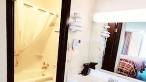 A hotel bathroom with a shower, toilet, and sink. - Roadside Inn (Osceola)