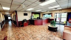 A spacious lobby with a reception desk, a seating area, and a large window offering a view of the outdoors. - Roadside Inn (Osceola)