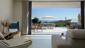 Un salon moderne doté d’une grande porte-fenêtre coulissante qui donne sur un espace de détente extérieur offrant une vue sur les montagnes.