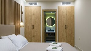 Une chambre à coucher comprenant un lit, deux armoires en bois, un miroir rond, et une salle de bain avec un lavabo et un miroir.