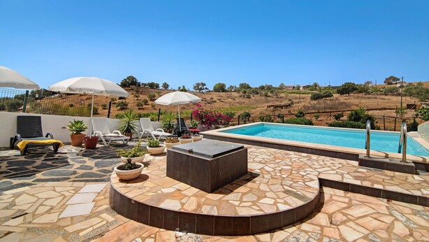 A poolside area with a stone patio, lounge chairs, umbrellas, and a view of the surrounding landscape. - Pet-Friendly Villa 'Casa dos Jotas' with Pool & Wi-Fi (Martinlongo)