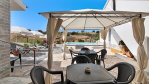 An outdoor patio with tables and chairs, a pool in the background, and a view of a hilly landscape. - Pet-Friendly Villa 'Casa dos Jotas' with Pool & Wi-Fi (Martinlongo)