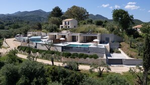 A modern villa with a pool, outdoor seating, and a view of the surrounding hills.