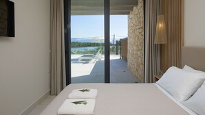 A hotel room with a bed, a view of a balcony with a table and chairs, and a stone wall.