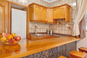Eine Küche mit Holzschränken, einem Edelstahl-Spülbecken und einer Obstschale auf der Arbeitsfläche.