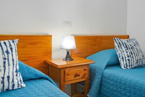 A bedroom with a wooden headboard, a bedside table with a lamp, and blue bedding.