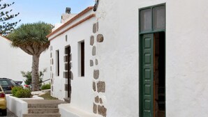 Un bâtiment blanc avec une porte verte, des marches en pierre et un palmier.