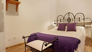 Une chambre à coucher comprenant un lit, une table de chevet, une chaise et un téléviseur fixé à une étagère.