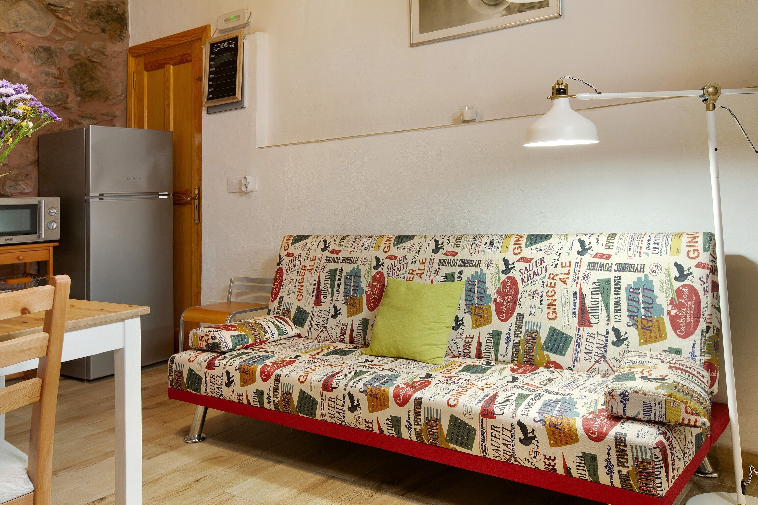 Una kitchenette pequeña con microondas, refrigerador y una silla de madera.