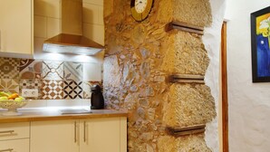 Une cuisine avec des murs en pierre, une horloge et un pare-feu en carreaux.