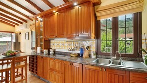 Une cuisine avec des meubles en bois, un plan de travail en granit et une fenêtre donnant sur un paysage verdoyant.