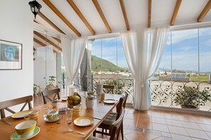 Un coin repas avec une table dressée pour quatre personnes, un balcon avec vue et une plante en pot.