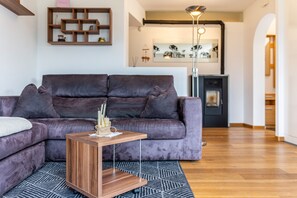 Een moderne woonkamer met een donkerbruine bank, een houten bijzettafeltje en een kamerbreed tapijt met dessin.