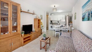 A living room with a TV, wooden cabinets, a sofa, and a small table with a plant. - Vacation Apartment 'Puertito Guimar' with Shared Terrace, Balcony and Wi-Fi (Guimar)