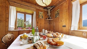 A wooden room with a table set for breakfast, including bread, pastries, and condiments.