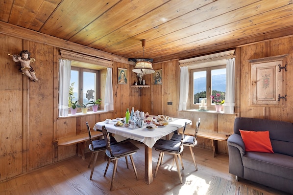 Un intérieur en bois comprenant une table à manger, des chaises, un canapé et des fenêtres offrant une vue.