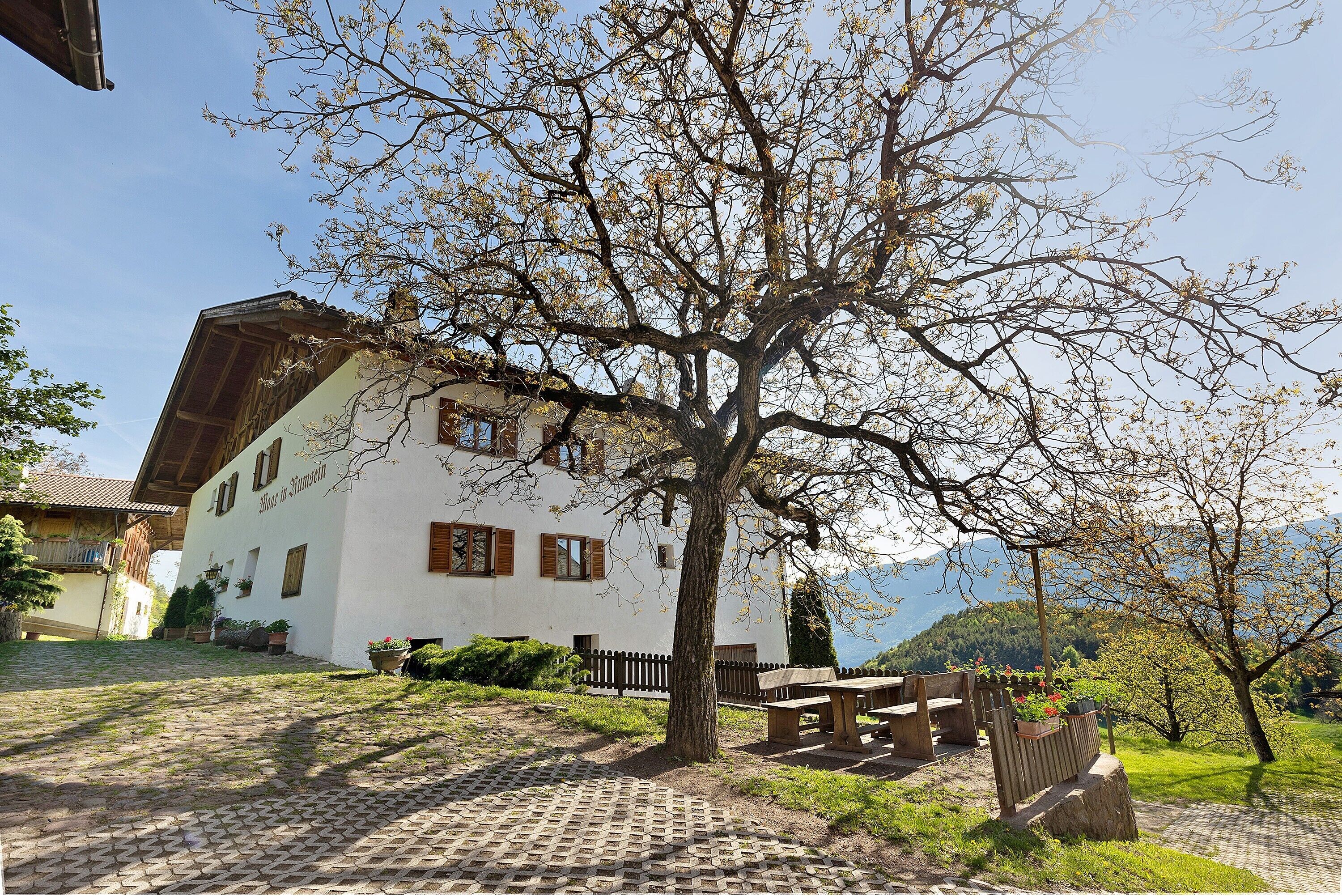 Un edificio bianco con tetto spiovente, una recinzione in legno e una panchina.