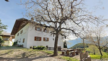 Un edificio bianco con tetto spiovente, una recinzione in legno e una panchina.